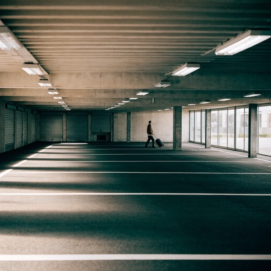 Empty interior parking level of an airport car park with painted bay divisions and a ribbed low ceiling under hard overhead light